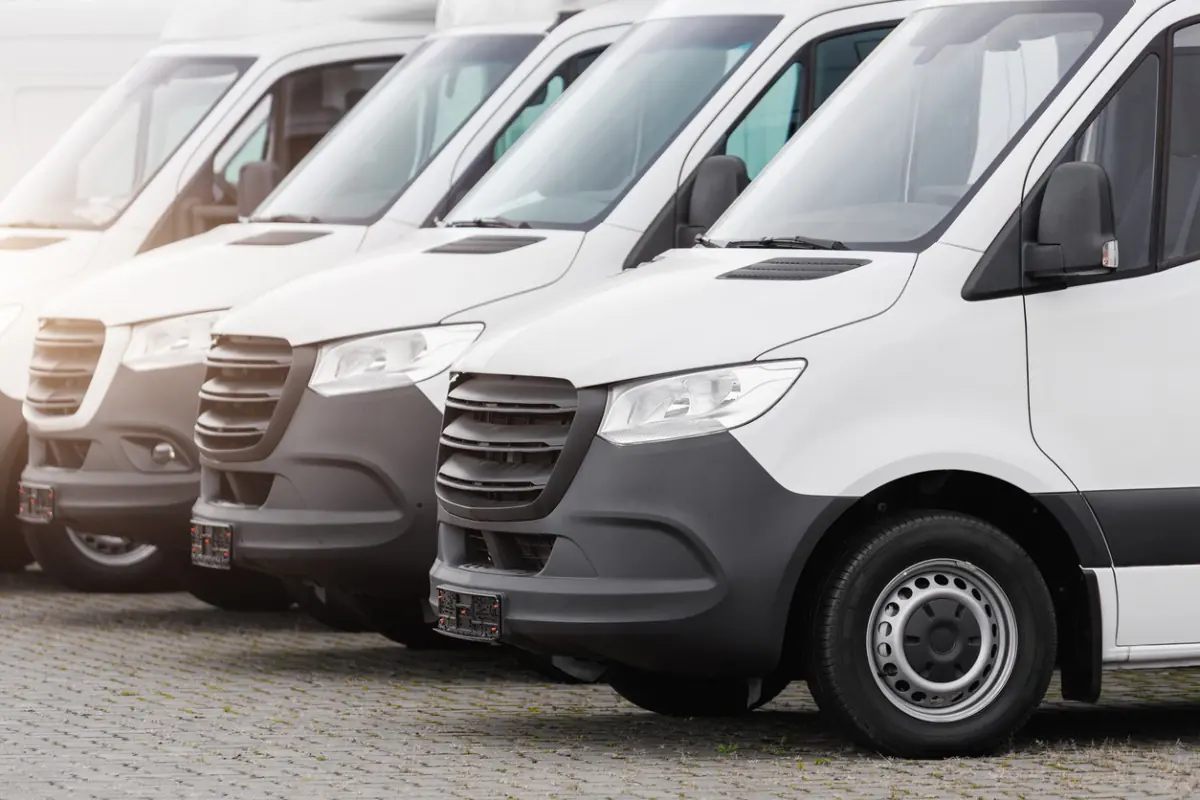 Row of white pickup and delivery vans parked side by side