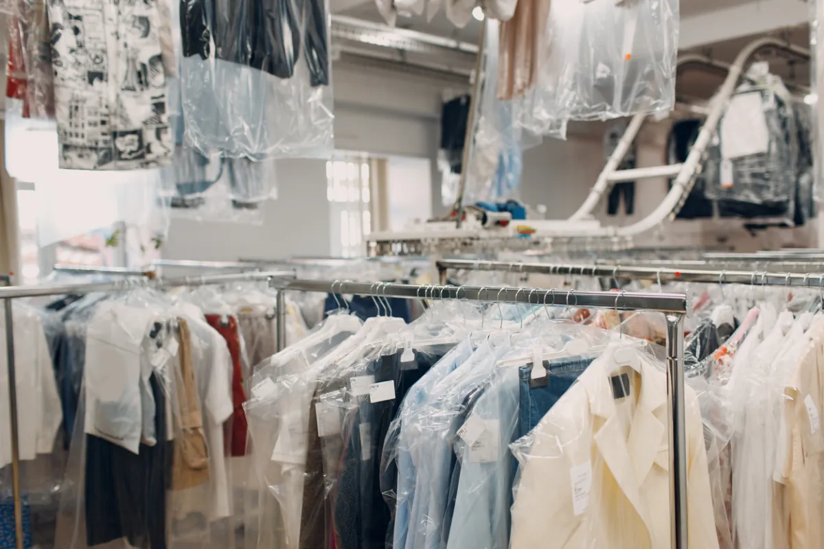 A professional cleaner inspecting freshly cleaned garments